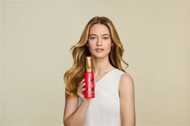 Image displaying woman holding OGX® Bond Protein Repair 450°F Heat Protect Spray"