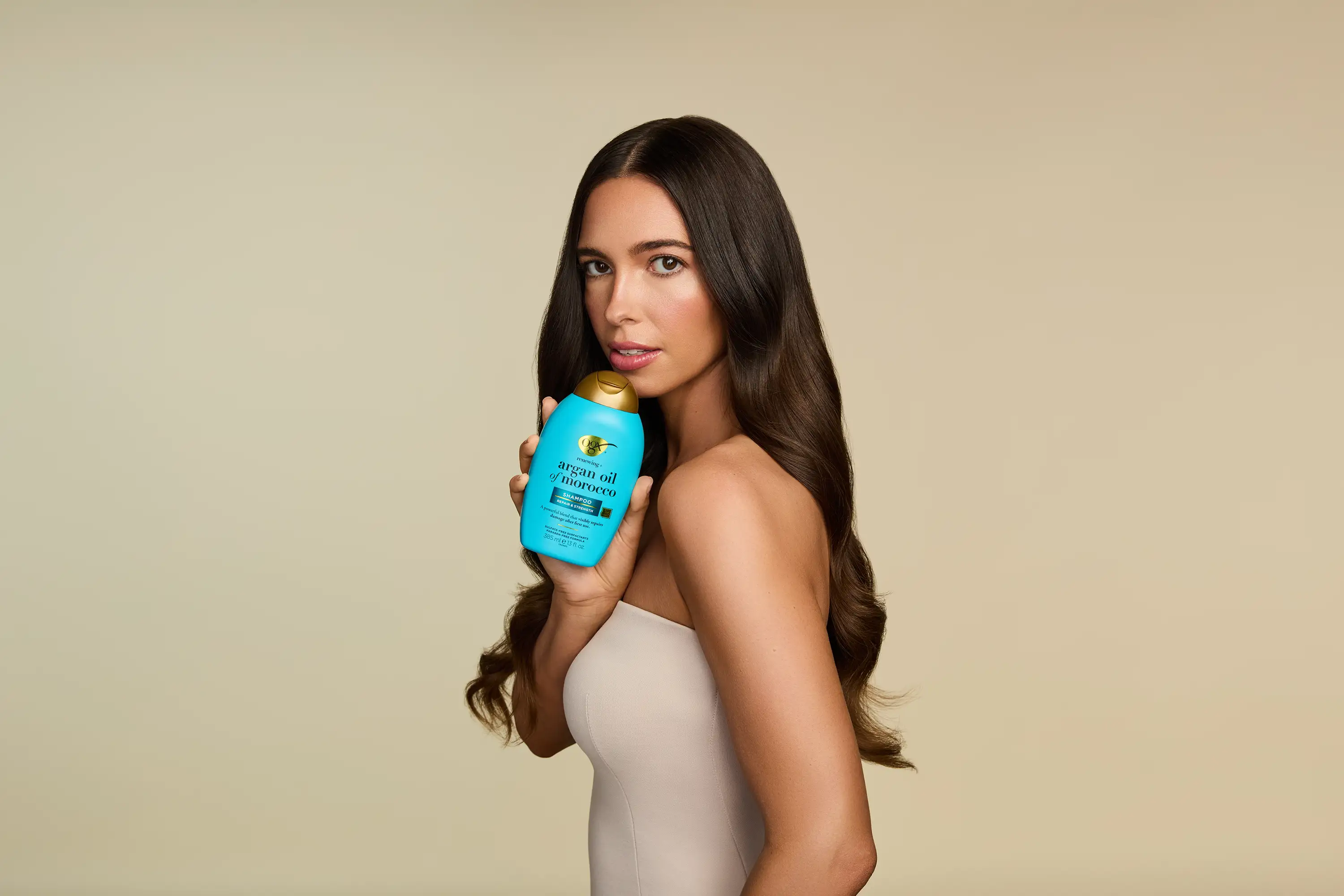 Woman with Shiny Hair holding OGX® Argan Oil of Morocco Shampoo