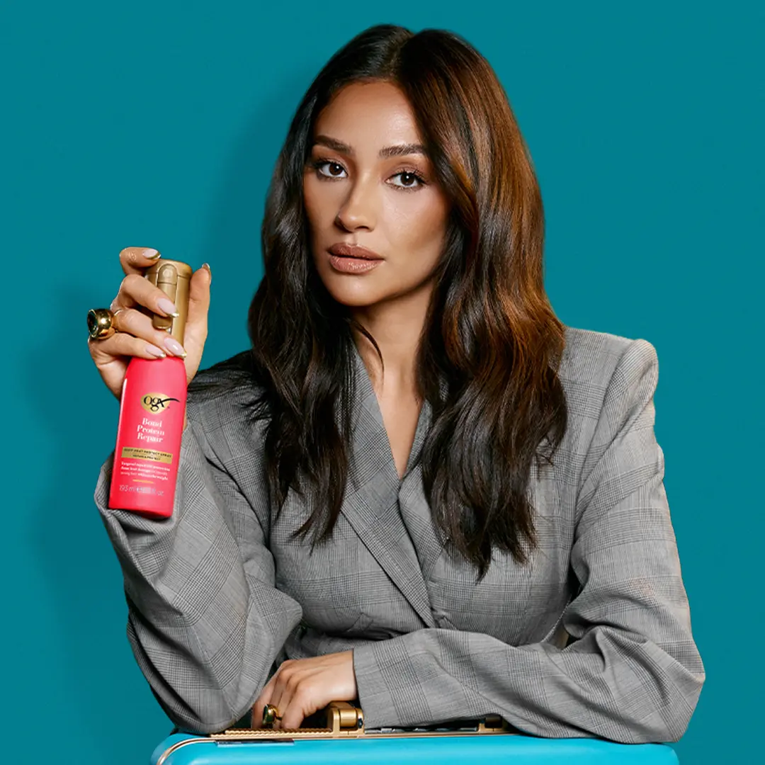 Image of Shay Mitchell holding OGX® Bond Protein Repair Heat Protect Spray