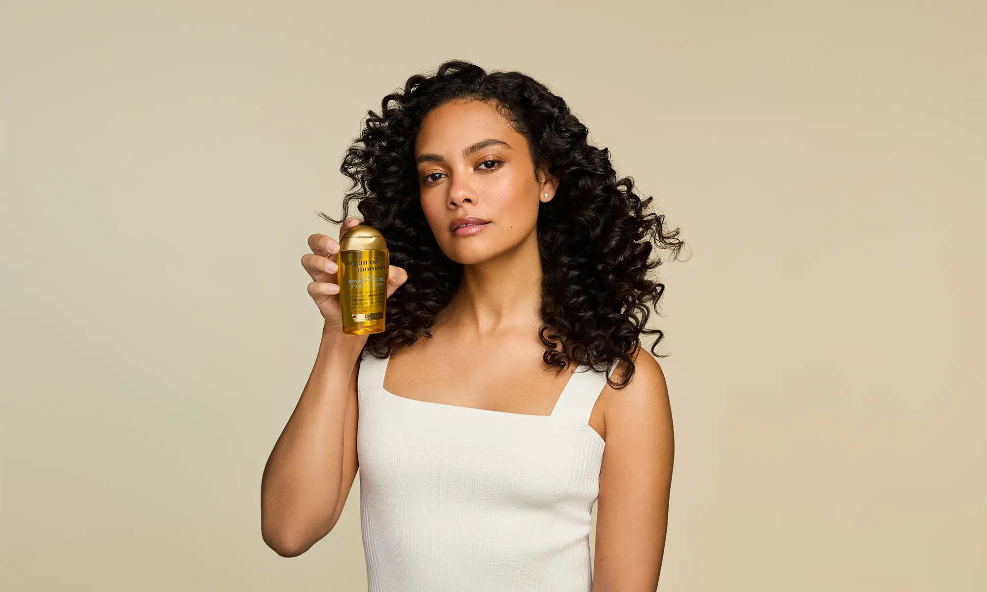 Woman with healthy hair holding OGX® Argan Oil of Morocco Extra Penetrating Oil