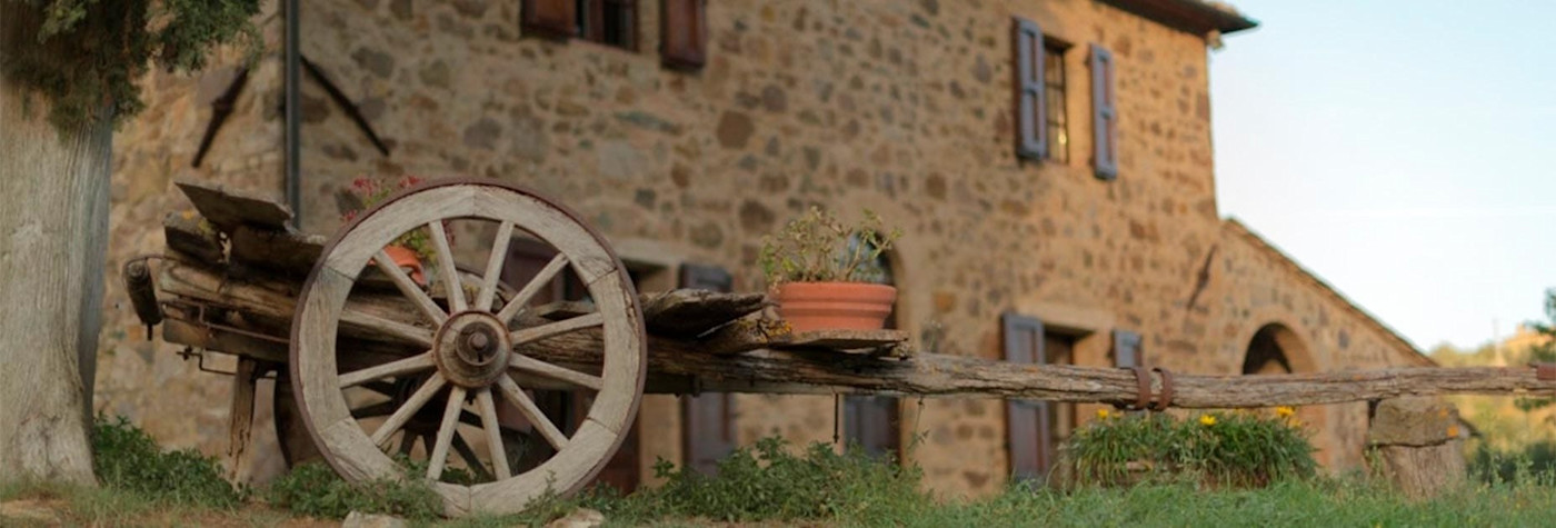 Steinhaus mit einem Holzwagen davor auf dem Weingut Le Macioche
