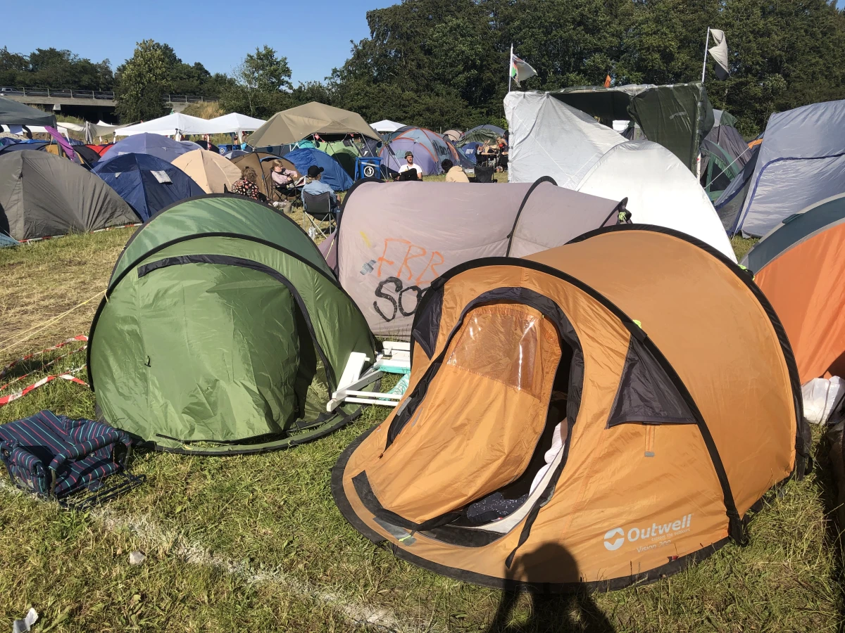 Sebastian sover selv i et pop-up-telt til 1.500 kroner. ’Det tog jeg engang på festivallen, selvom der var meget bræk på, og nu er det 5. år i streg, jeg sover i det på festivallen. Så det har minimum været 6 år på Roskilde Festival, men det er også ved at dø nu’, siger han, der i år tilbød teltet gratis til en ven. Sebastians telt er det beige i baggrunden på billedet. Det grønne og det orange telt er også pop-up telte i Sebastians lejr