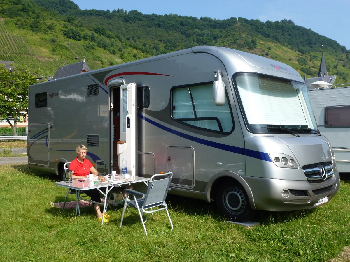 Her sidder Helle ved sin store autocamper med bjerge i baggrunden ved Mosel-floden i Tyskland, som er et af hendes bedste minder med vognen