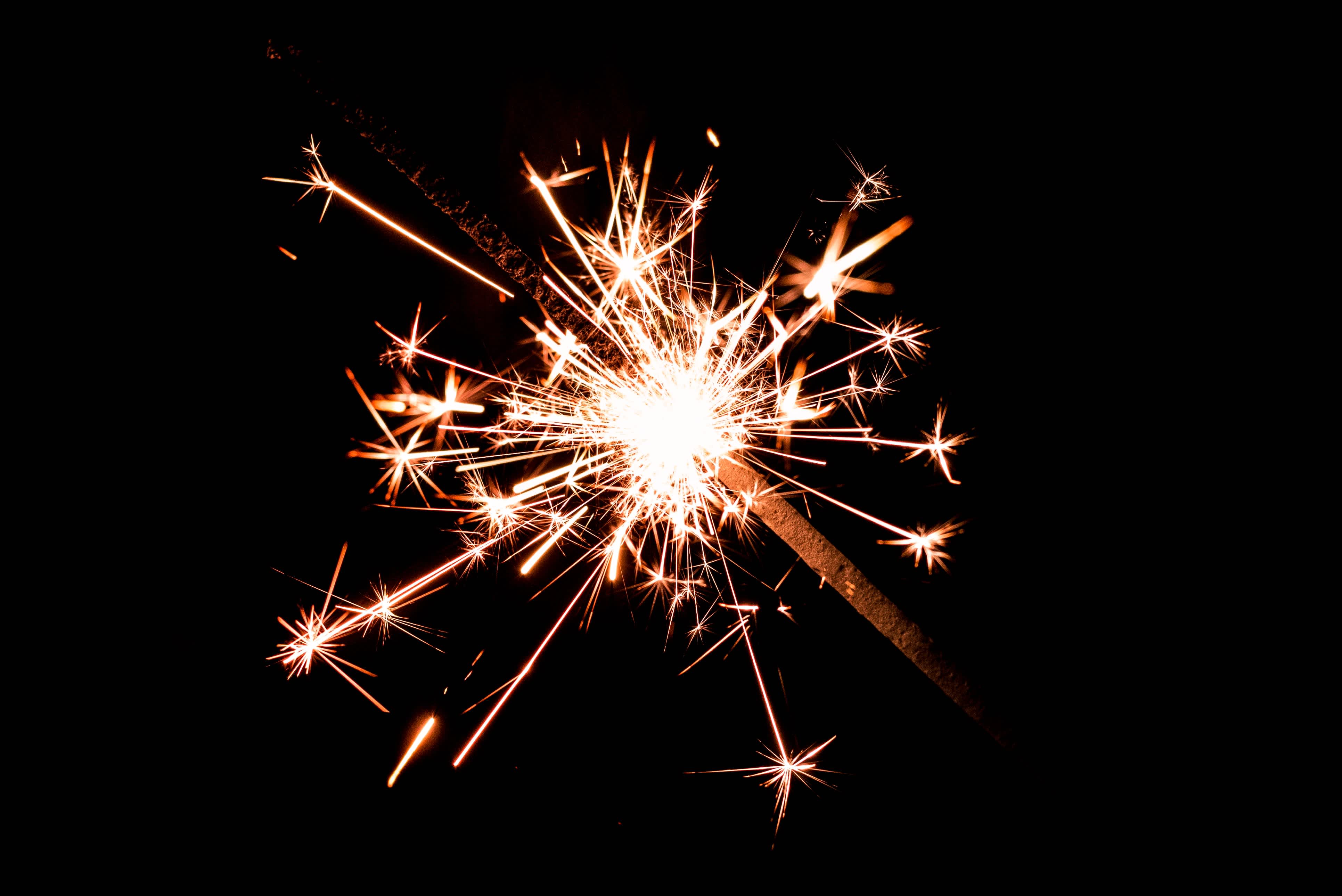 A photo of a gold sparkler against a black background.