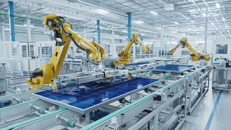 Robot arms work on an assembly line for solar panels