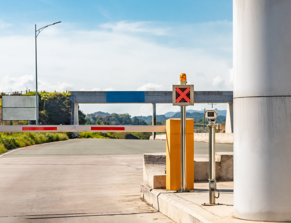 A photo of a toll booth gate with the bar down and a red x in the sign