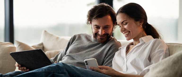 Mann og kvinne ser smilendes på mobiltelefon