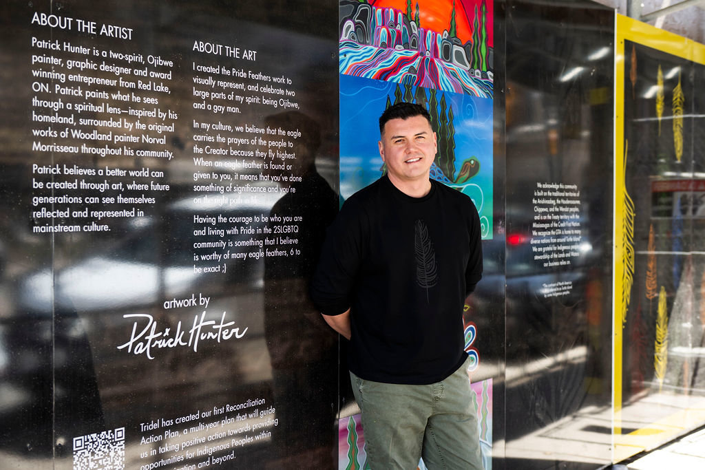Indigenous artist Patrick Hunter standing by his artwork on the hoarding of the Queen Church condominium community.