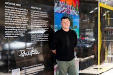 Indigenous artist Patrick Hunter standing by his artwork on the hoarding of the Queen Church condominium community.