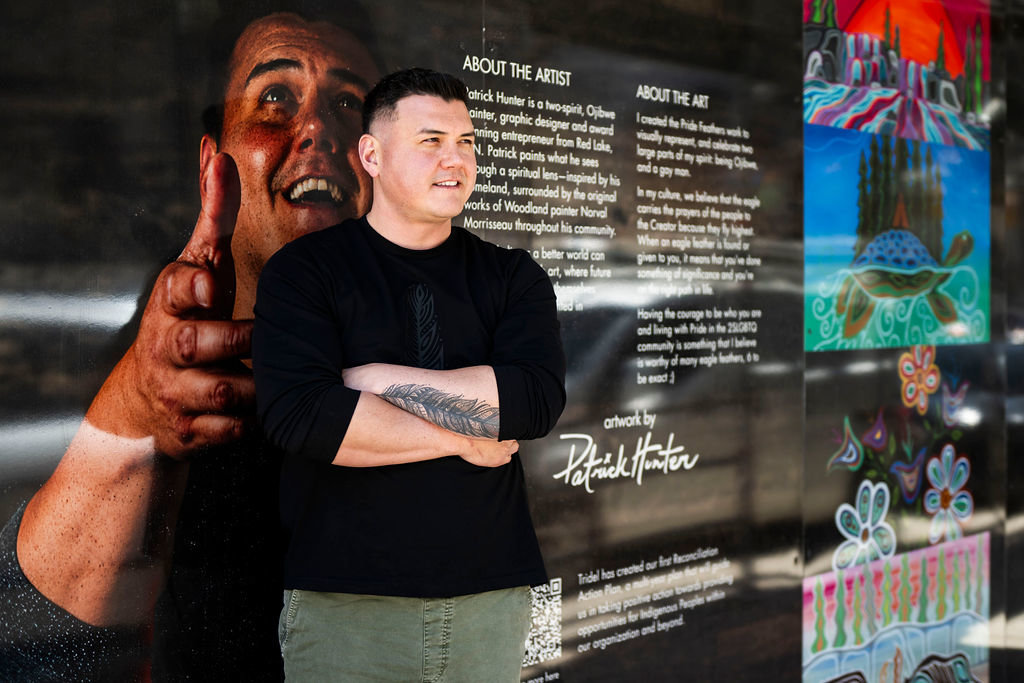 Indigenous artist Patrick Hunter standing by his artwork on the hoarding of the Queen Church condominium community.