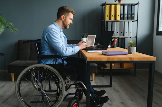 Man in wheelchair working at a desk