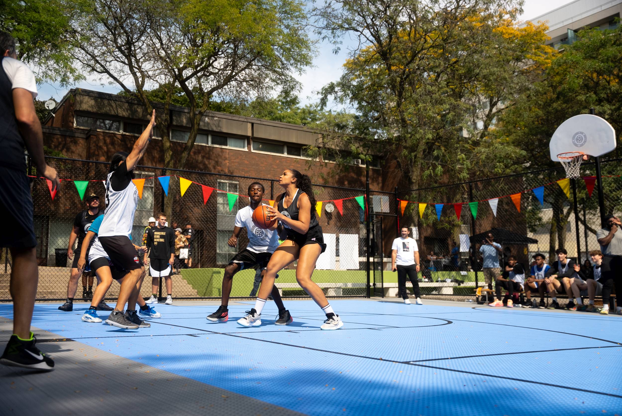 People enjoying a game of basketball on the newly refinished multi-sport court