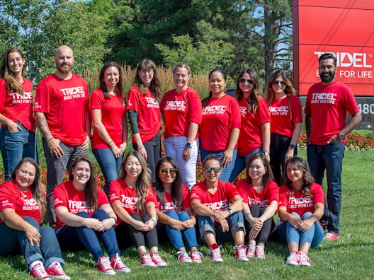 Tridel Staffs in red shirt standing in front of Tridel logo sign