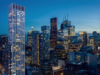 A Condo Building with many lights on with the a night time city skyline in the background