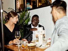 A group of friends conversing at a restaurant dinner table