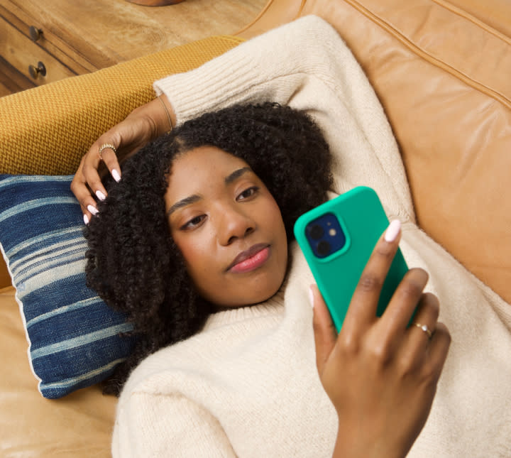 Woman scheduling appointment for UTI treatment online on her mobile phone while lying on couch