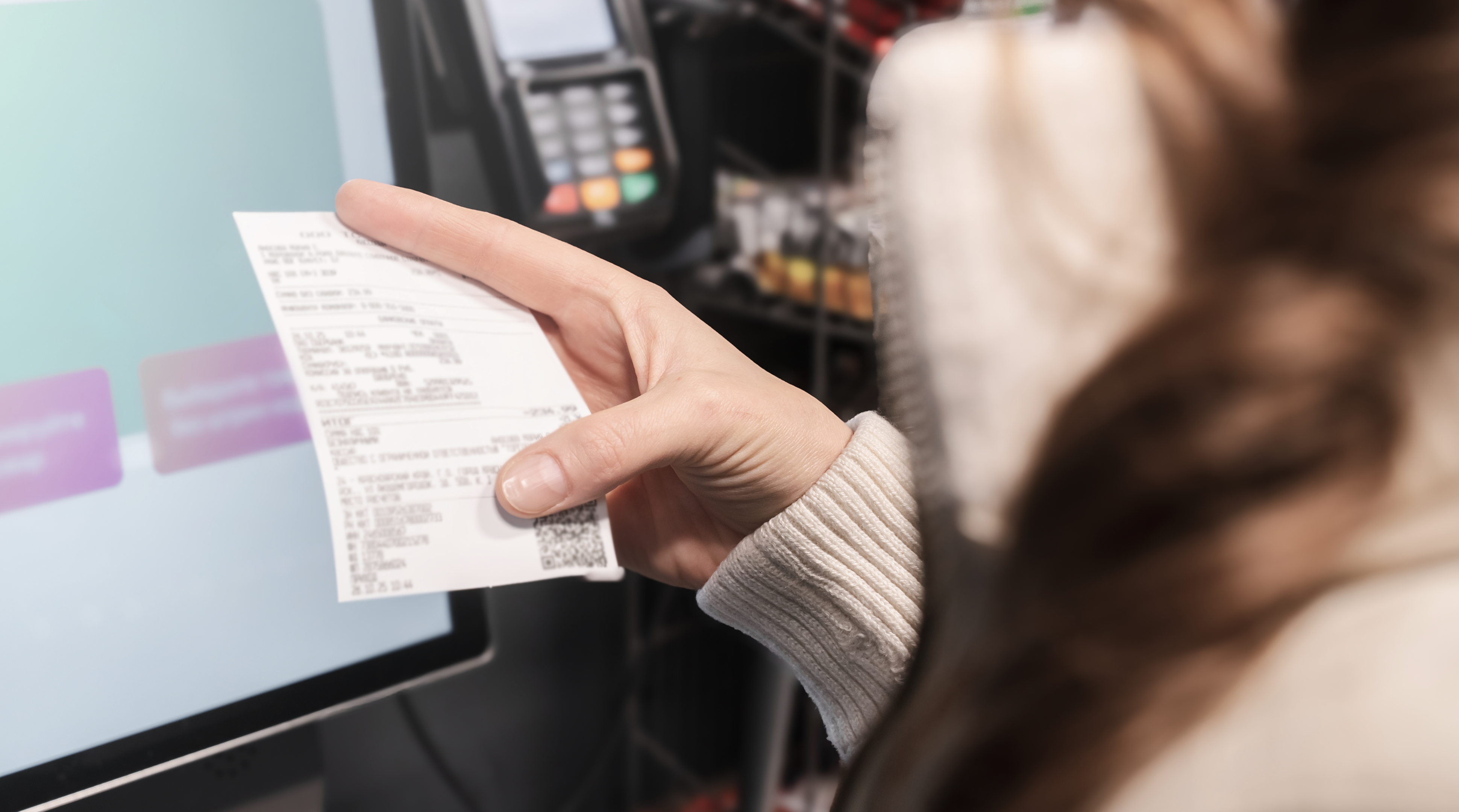 Woman examines her receipt closely at a self-service checkout while using the touchscreen display in a retail environment. Managing household expenses