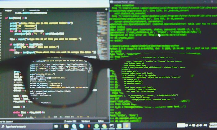 A pair of glasses in front of a computer displaying code.