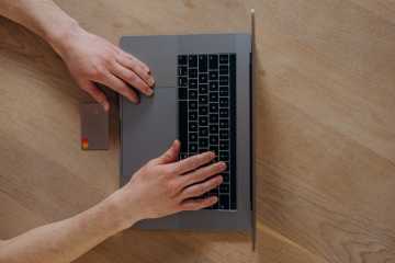 A person using a laptop beside a credit card