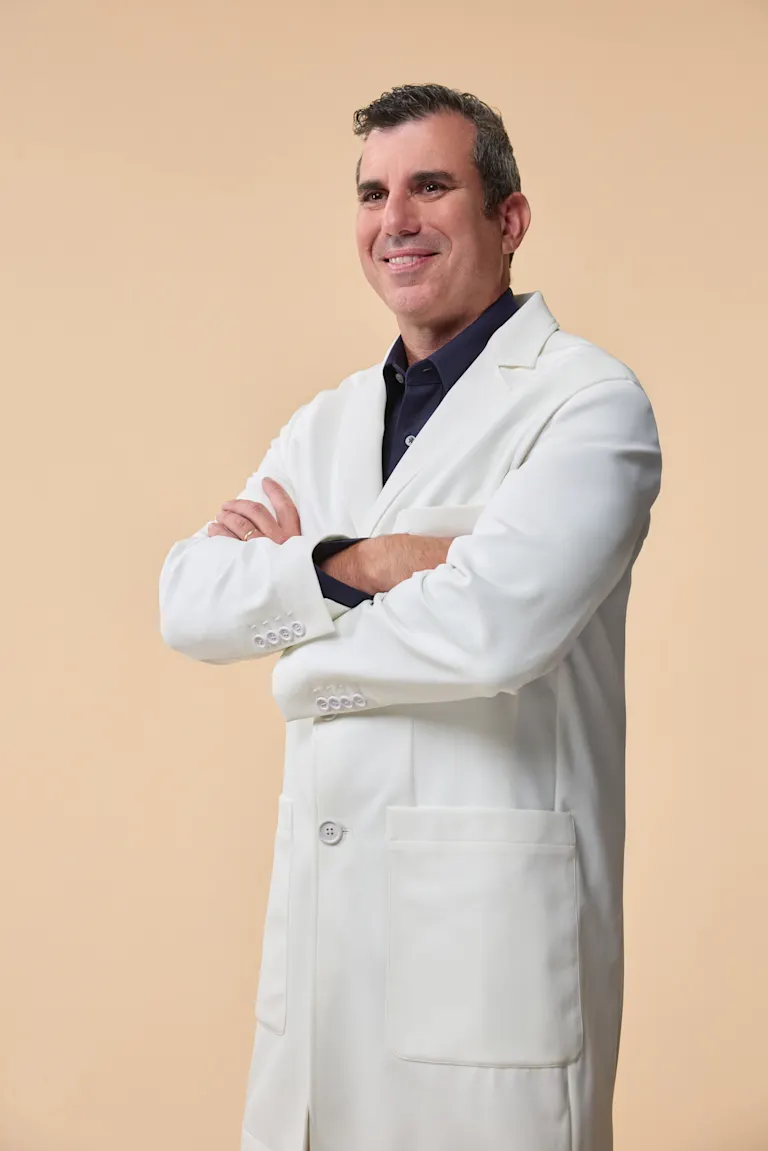 Doctor sits at desk with stethoscope and smiles to camera