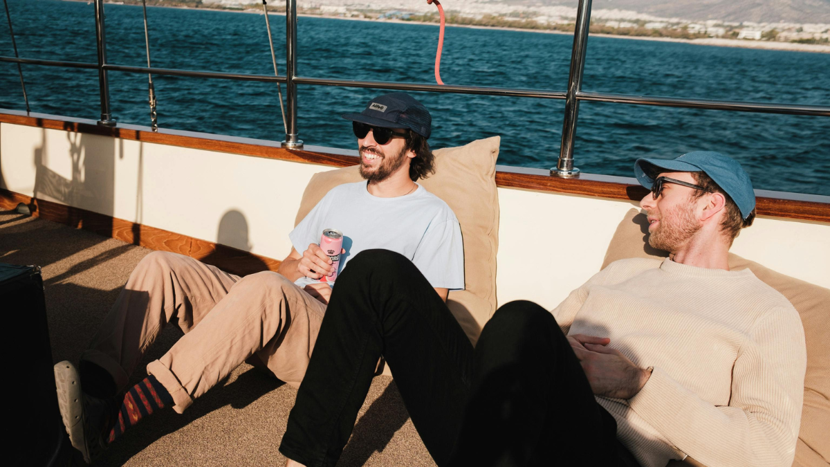 Two men relaxing on a boat drinking lower-calorie canned drinks instead of beer