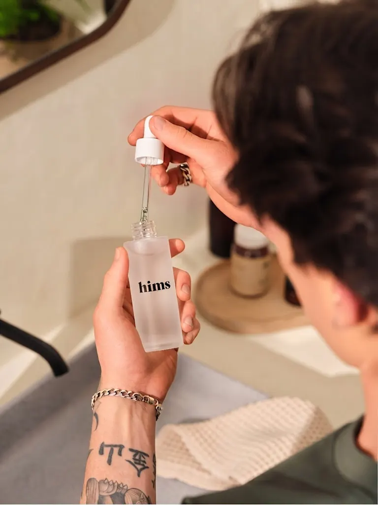 A man using acne treatment by Hims from a dropper