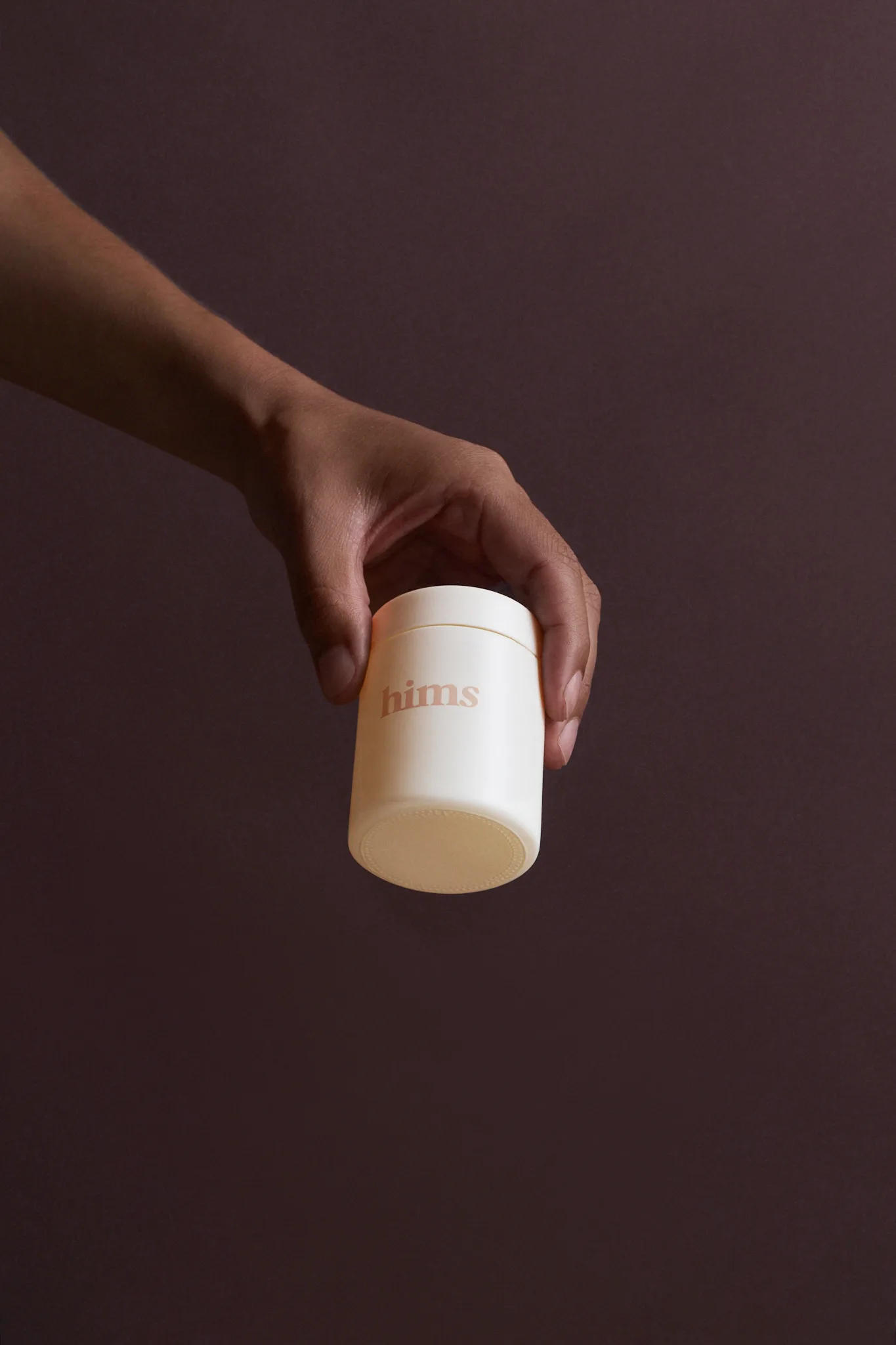 Man holding a jar of hair loss treatment plan by Hims