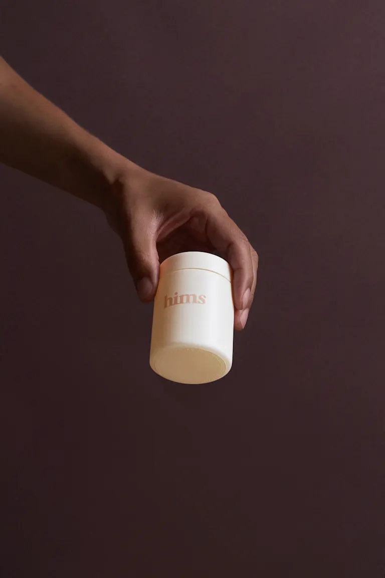 Man holding a jar of hair loss treatment plan by Hims