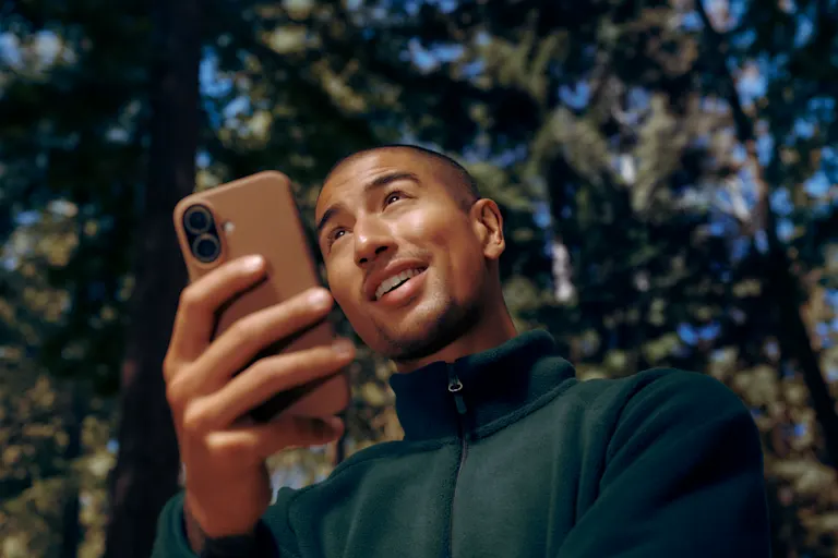 Man out in nature looking happily up from his phone