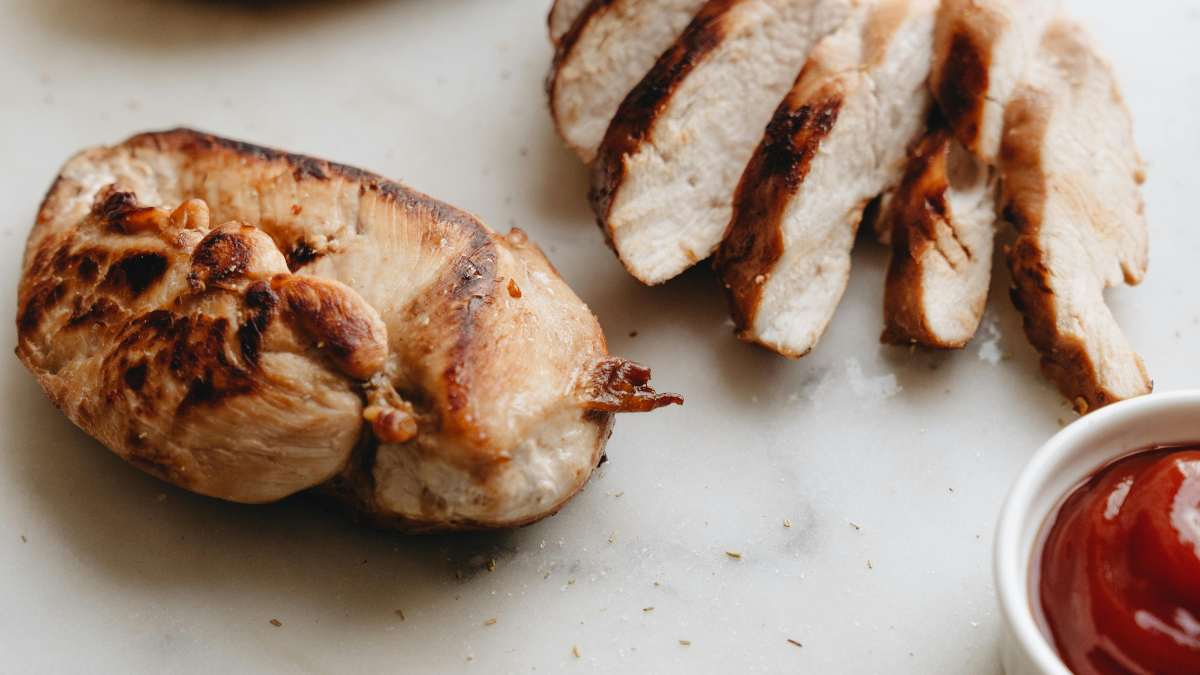 Grilled chicken breast sliced on a chopping board, a palm-sized portion of lean protein