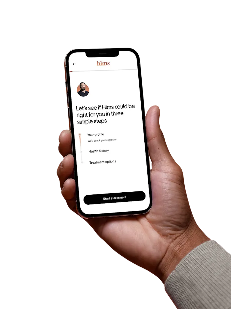 Hand holding a phone showing the Hims app