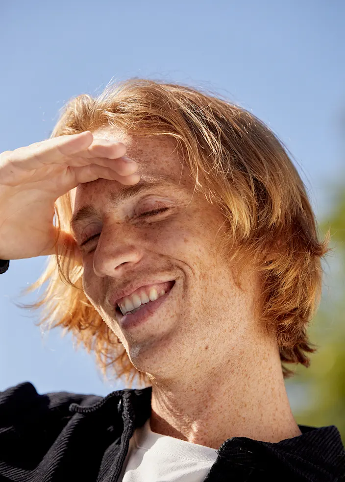 A person sitting in the sun covering his eyes