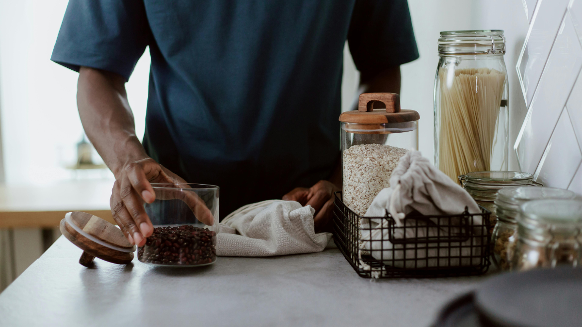Man filling pantry jars with fibre-rich foods like beans, oats and wholegrain pasta