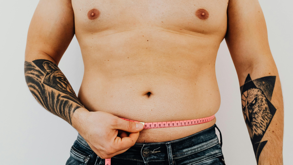 Man measuring his waist with a tape measure to track belly fat loss