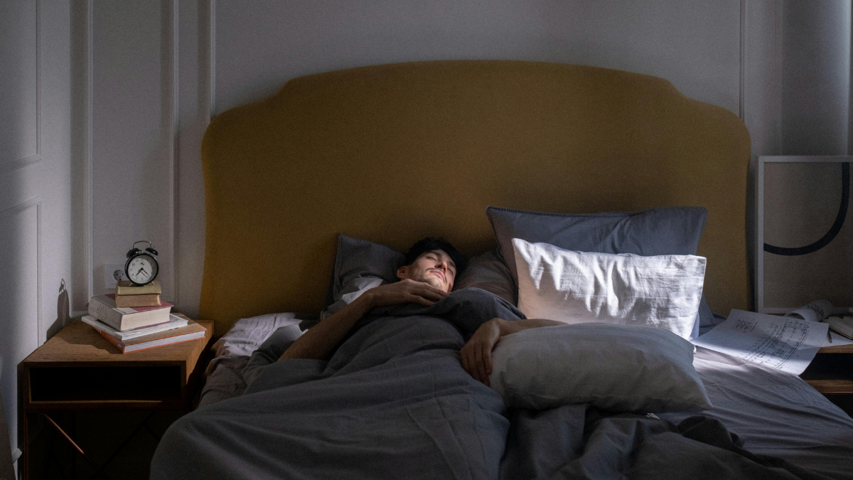 Man sleeping soundly in bed, getting the seven to nine hours that support metabolism