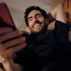 Guys laying down on the coach holding his phone
