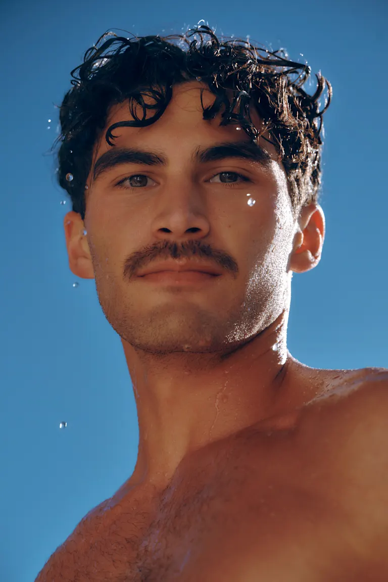 Shirtless man looks directly to camera