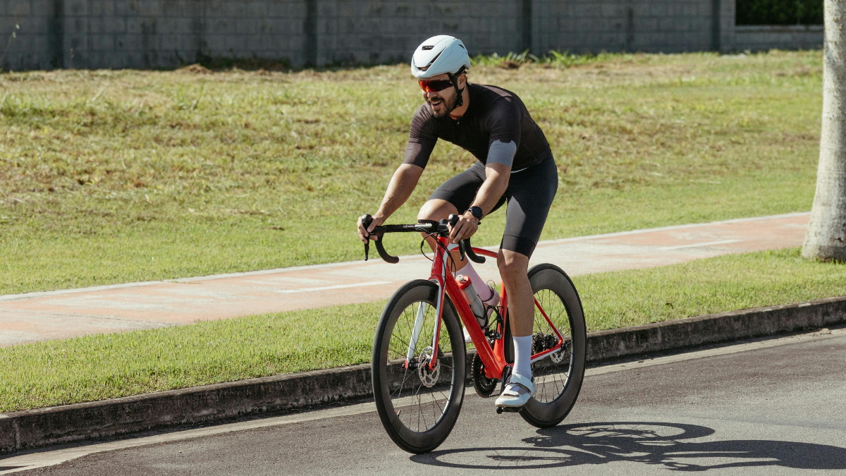 Man riding a road bike at speed, a form of high-intensity cardio for burning belly fat