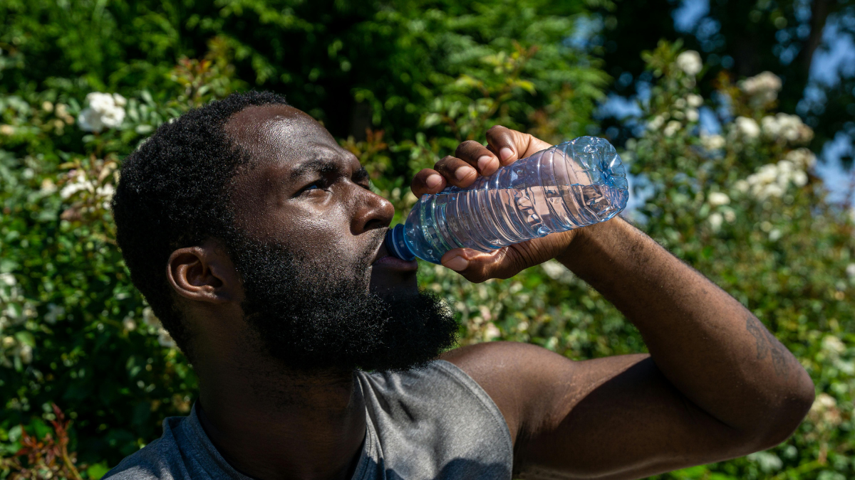 Man drinking from a water bottle outdoors instead of a sugar-sweetened drink