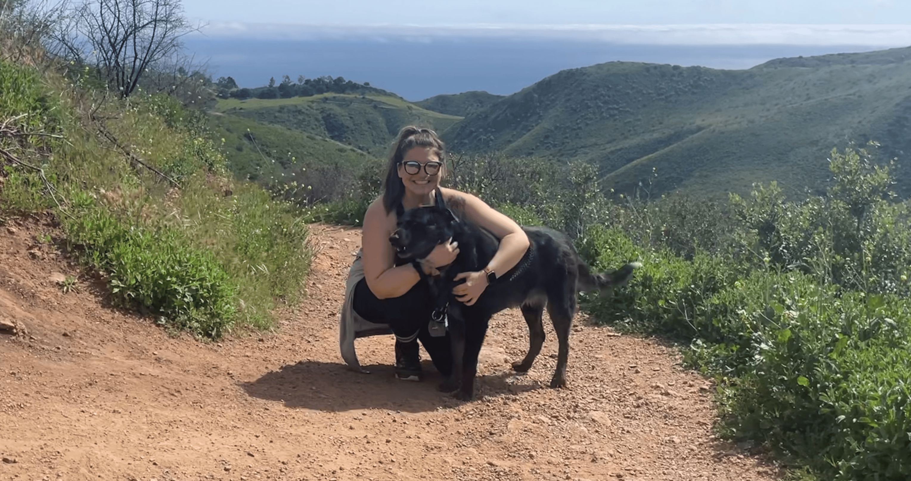 Sam hiking on a mountain trial with her dog.