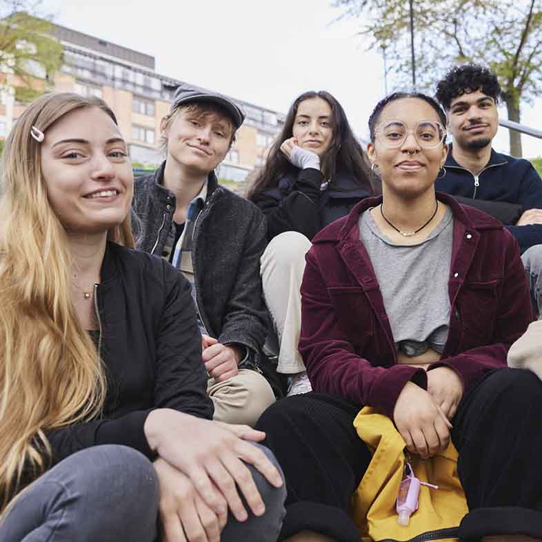 Fem ungdomar sitter ner i en trappa utomhus