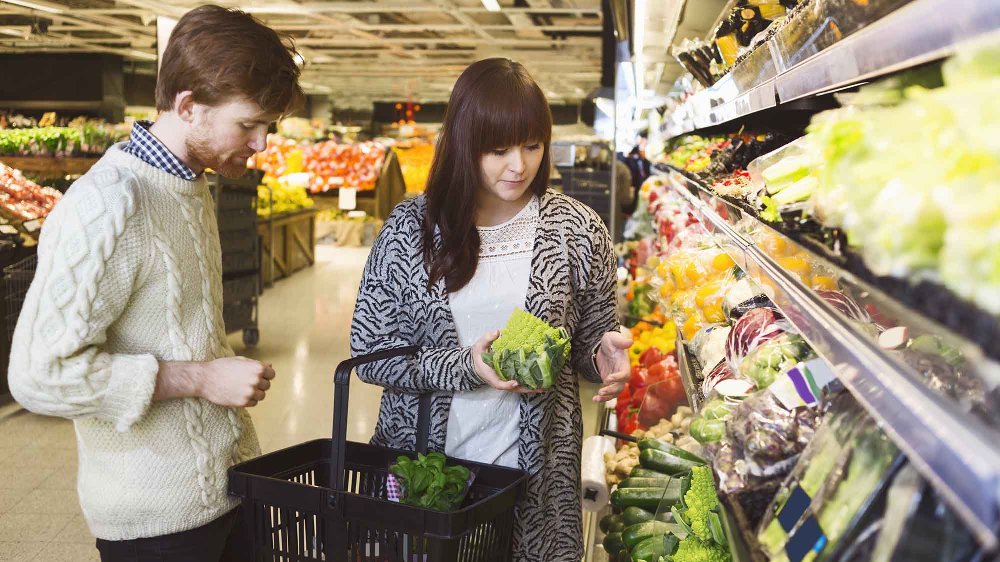 Två personer handlar grönsaker i en matbutik