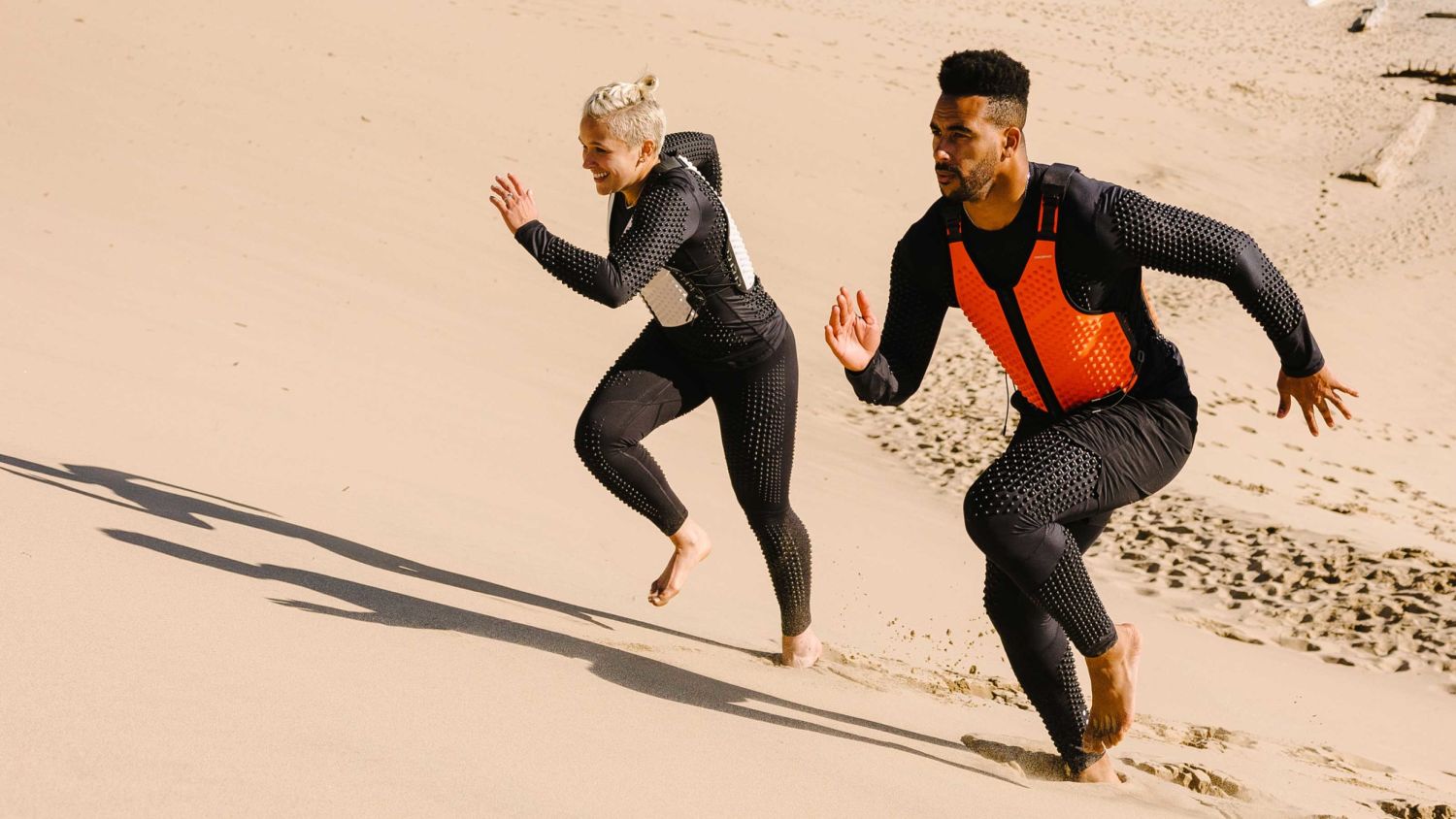 Man and Woman run up sandy hill in OMORPHO G-Vests