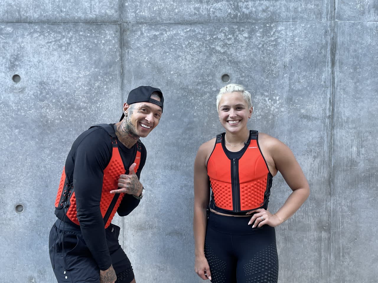 Quest Hawk and female trainer laugh and smile in OMORPHO weight vest, the G-Vest in Fire