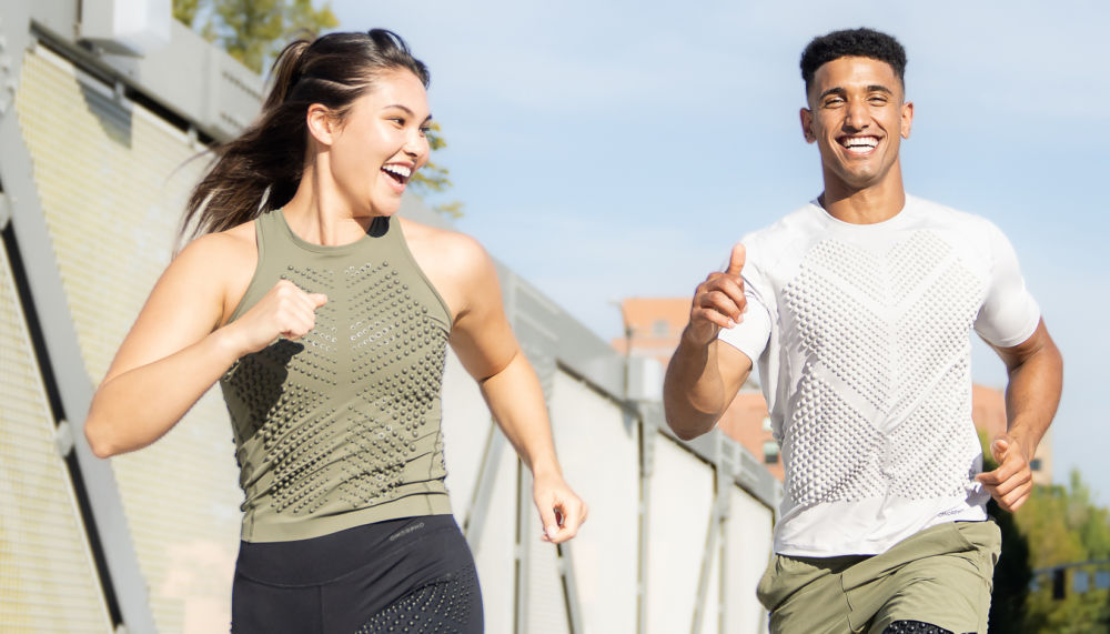 3-Up Desktop - couple has fun running outdoors in OMORPHO G-Tank olive, G-Top SS weighted top, G-Short olive and G-Tight