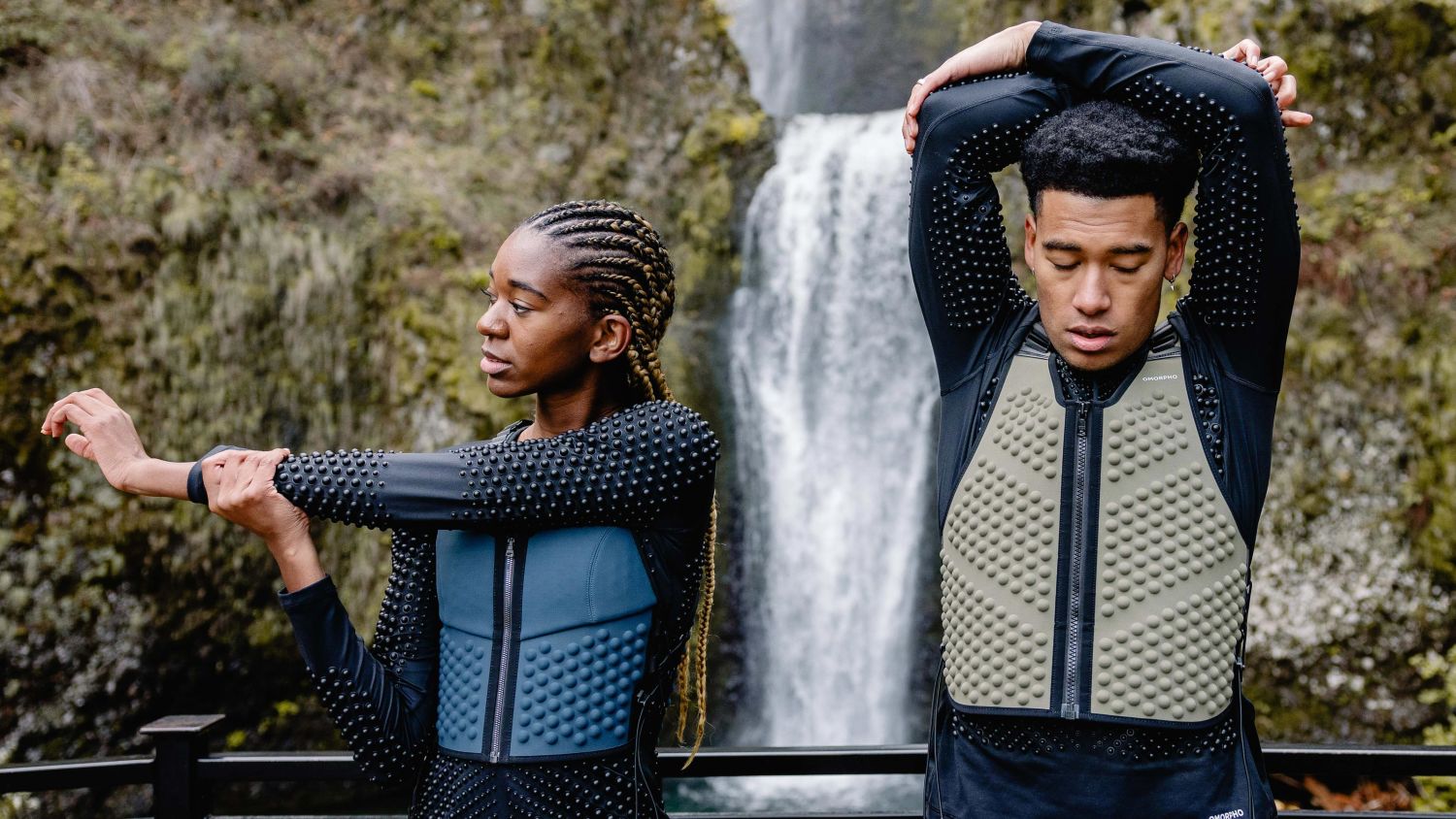 Man and woman stretching in OMORPHO G-Vest+ weighted vest for a workout. 