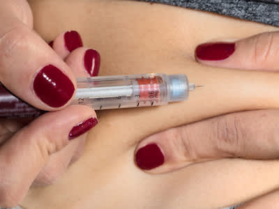 女人使用自动注射器给她胰岛素。