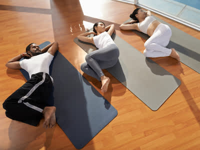在瑜伽课上做脊髓扭曲的三个人。