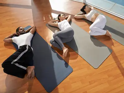 三个人在瑜伽课上做脊椎扭转。