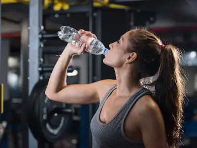 女人在健身房喝水。